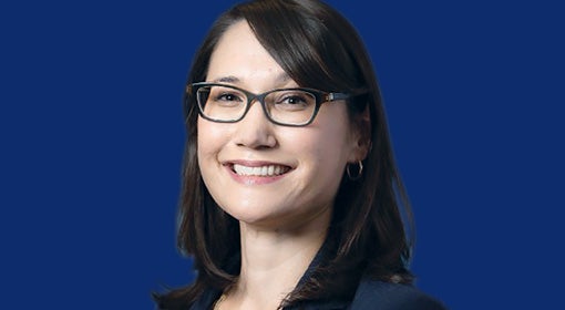 A smiling woman with black hair wearing glasses
