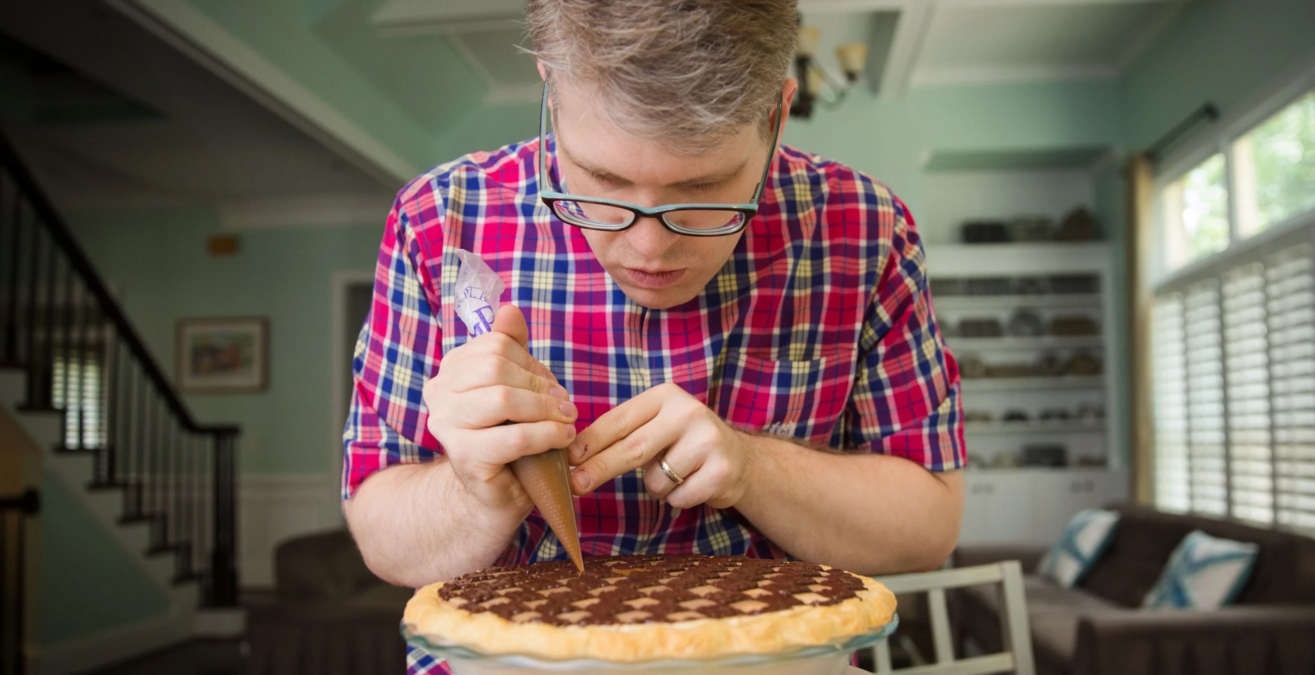 A person in a plaid shirt pipes onto a pie