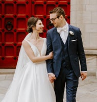 A bride and groom hug outside Heinz Chapel's red doors