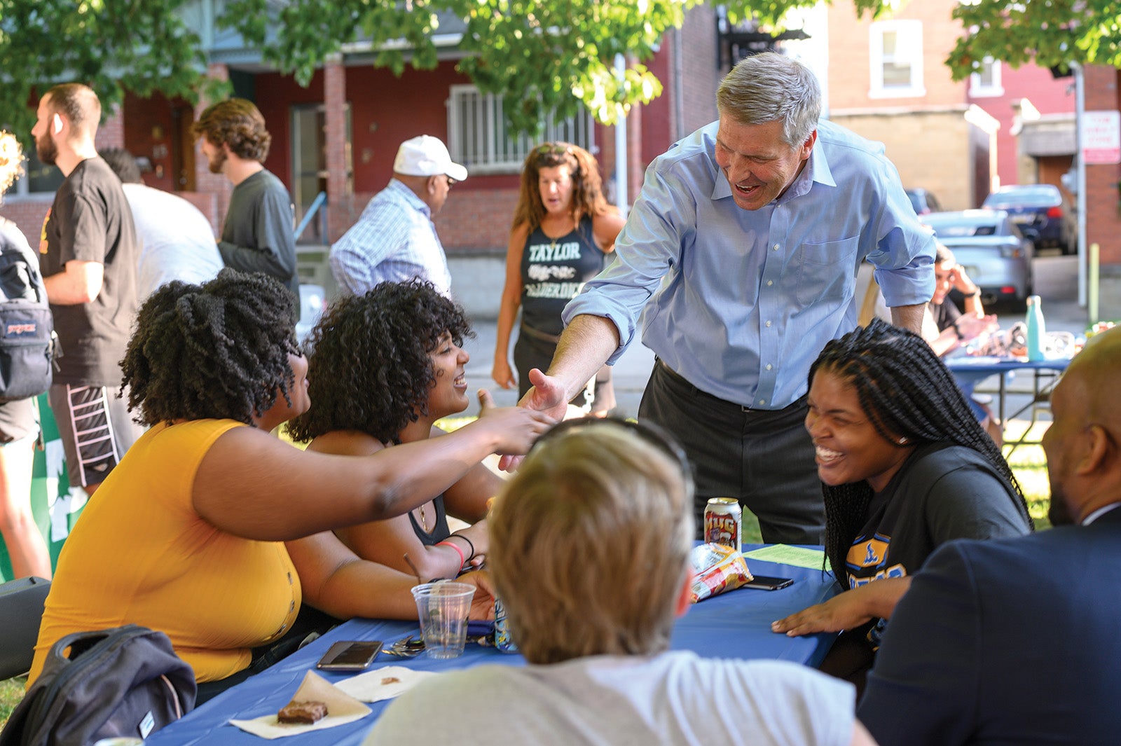 Gallagher shakes hands with people at a picnic table