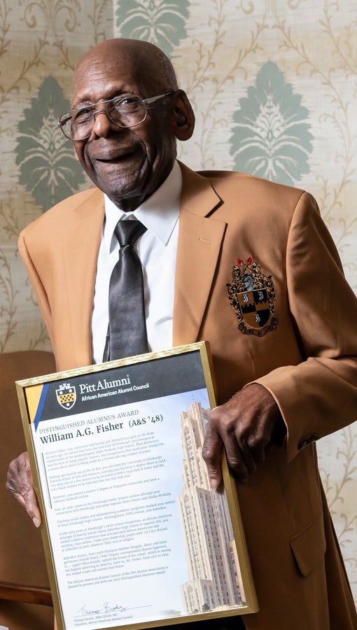 Fisher holds up his distinguished alumnus award 