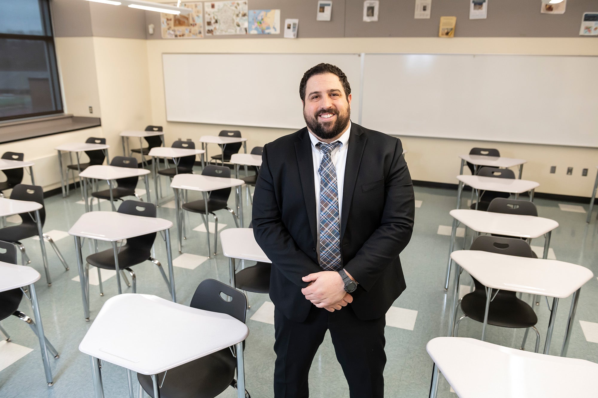 Villani stands in a suit in an empty classroom