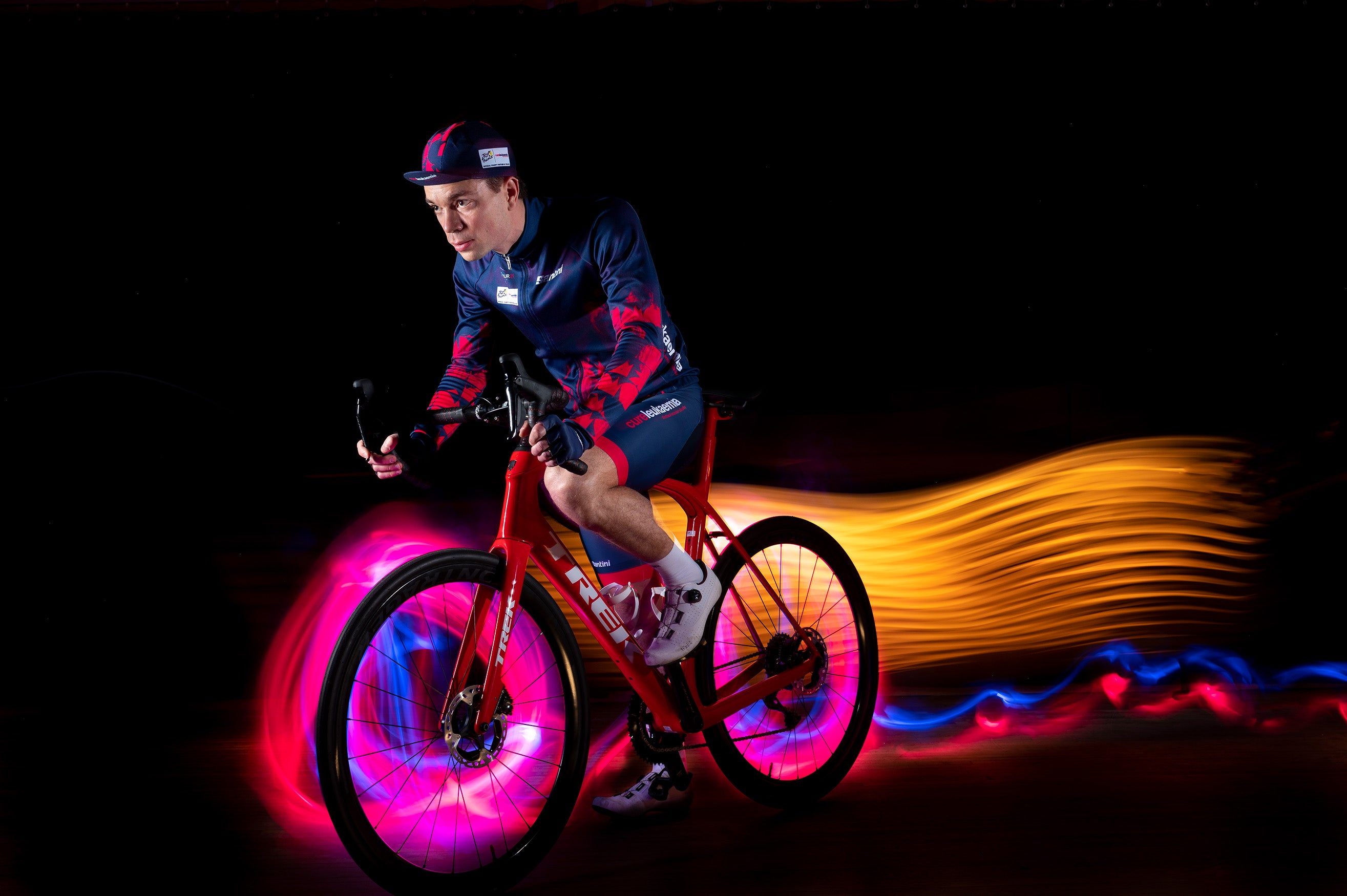 A photo illustration of neon lights surrounding Ian MacFawn riding his bike