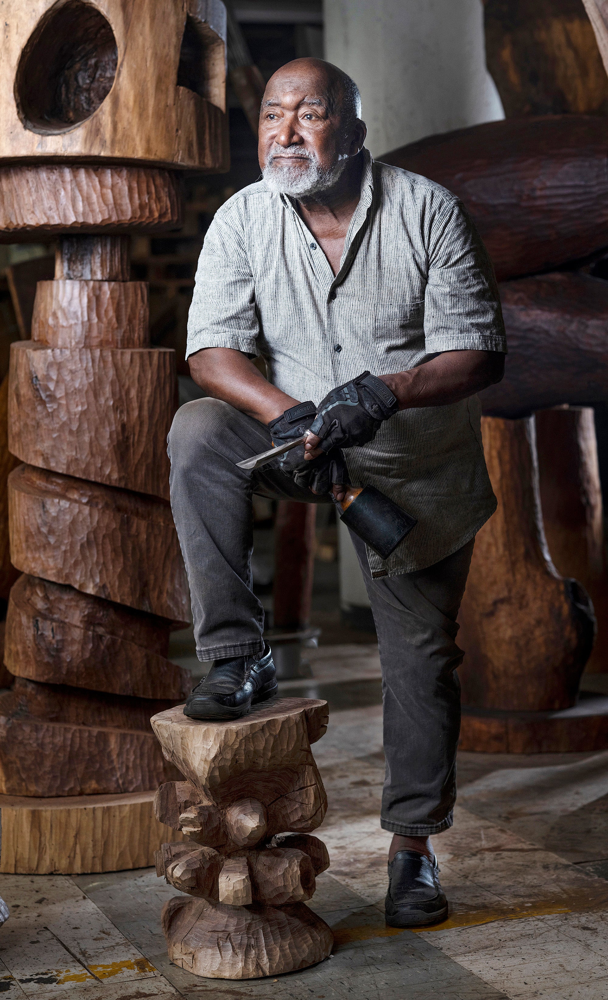 A man stands with his right foot on a wooden sculpture