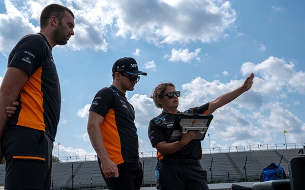 Gundlach gestures at the track as two team members listen