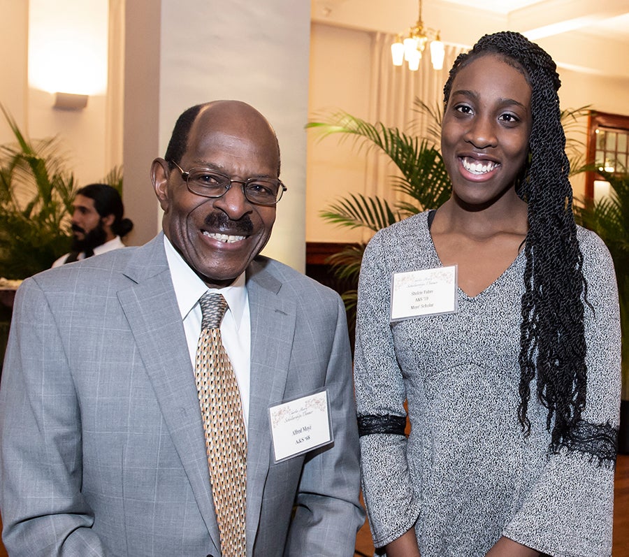 man in gray suit with tie and young woman in gray dress stand for photo in ballroom