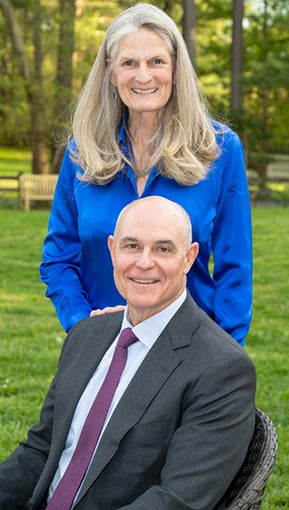 Sophia Lynn, in a blue shirt, stands behind David Frederick, who is seated