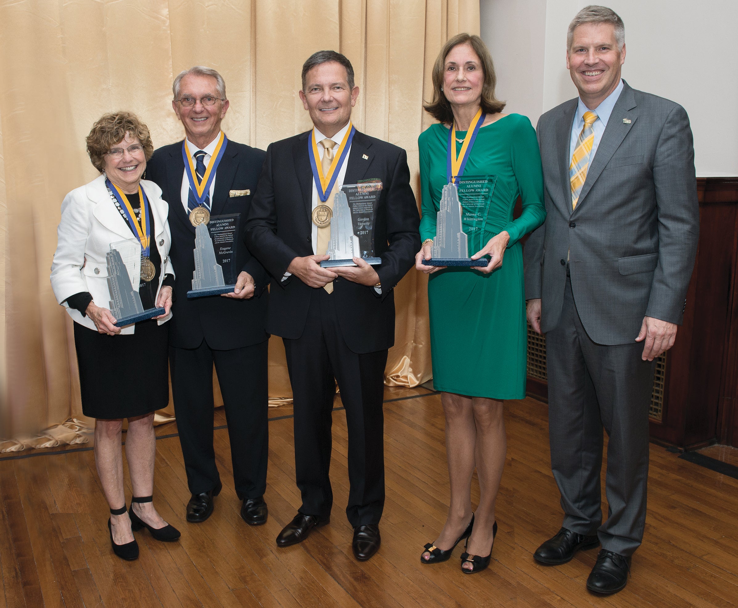 Alumni awardees each hold a trophy shaped like the Cathedral of Learning.