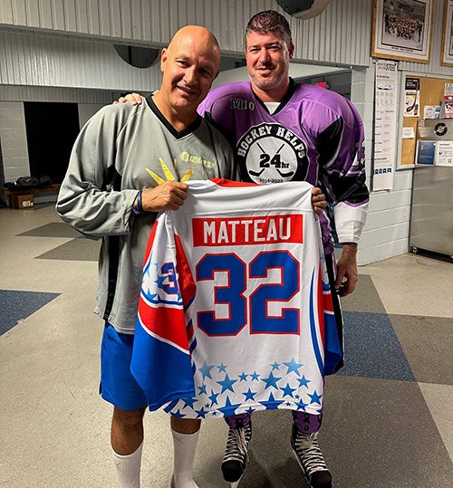 Salzer holds a Matteau jersey in front of the hockey player