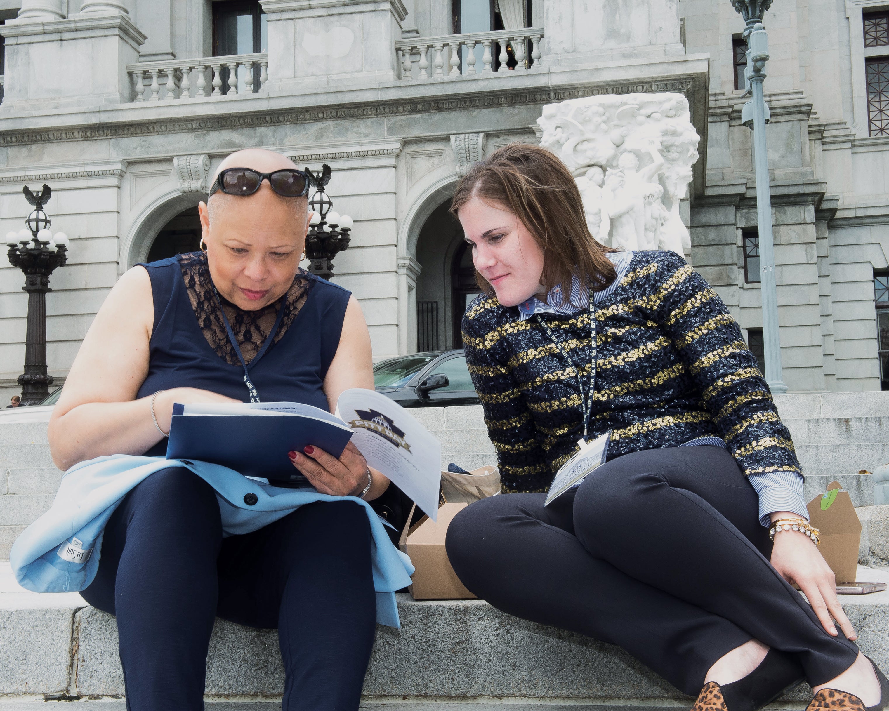Camille Burgess (CGS ’12) (left) and Victoria Ivock (UPJ ’17) reviewed materials on the steps of the Pennsylvania State Capitol building before speaking to lawmakers during the 2018 Pitt Day in Harrisburg. The annual day of advocacy connects legislators with Pitt alumni, faculty, staff, and students who share the many ways Pitt makes an impact.