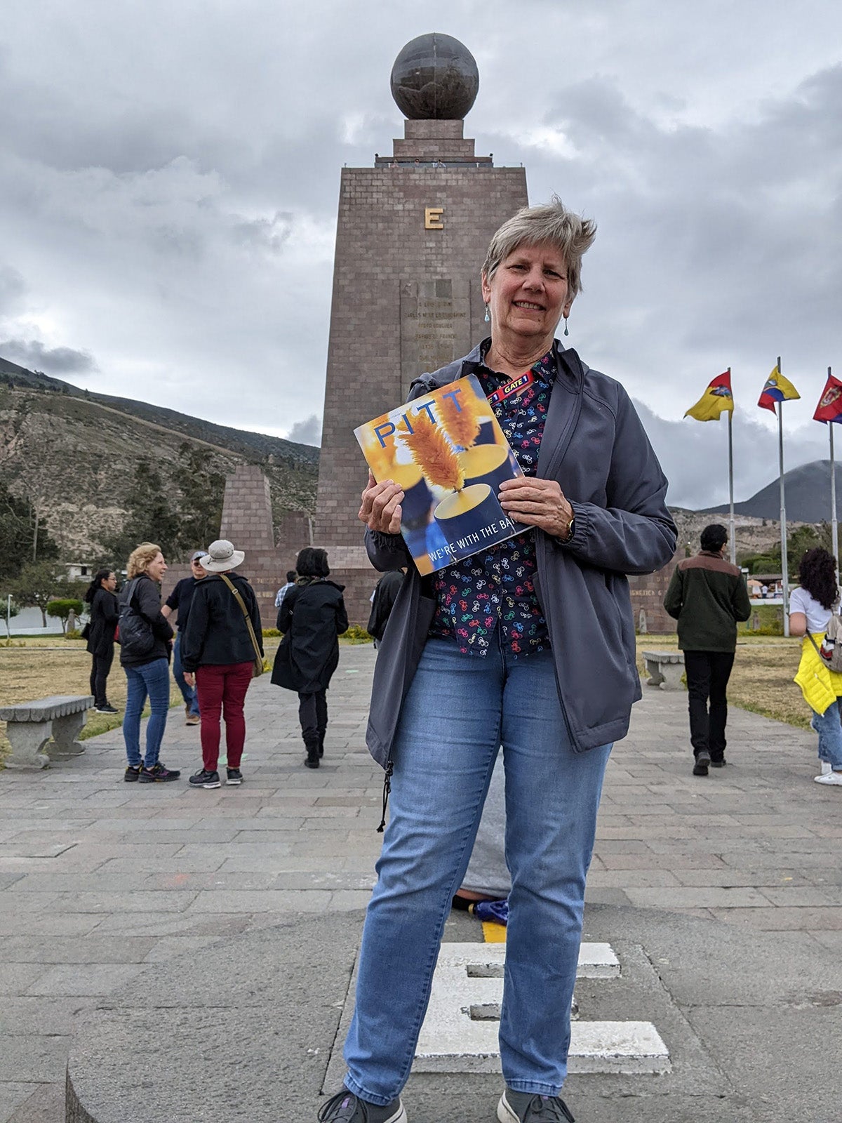 A person holds a magazine in front of a brick monument