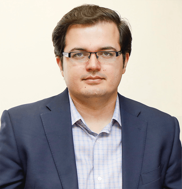 portrait of man in navy suit jacket, blue-striped button down and glasses