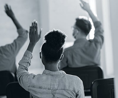 backs of students raising their hands