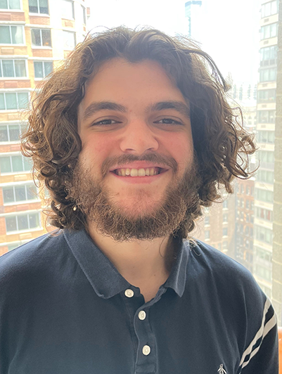 photo of young man with dark curly hair and beard smiling for camera