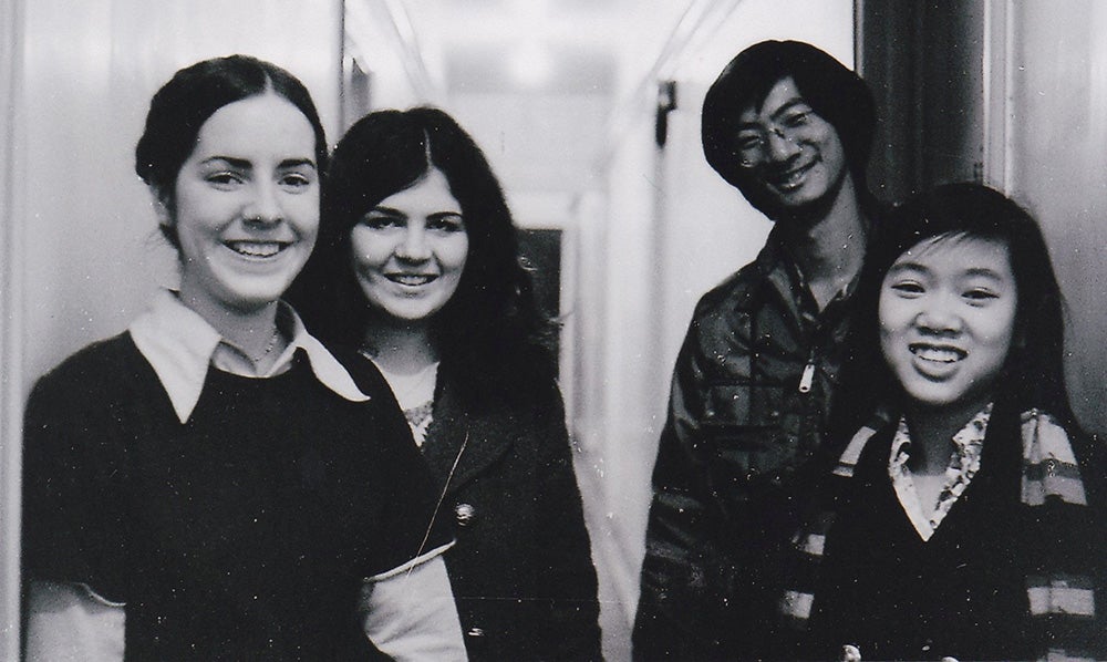 Four people smile in a black and white photo