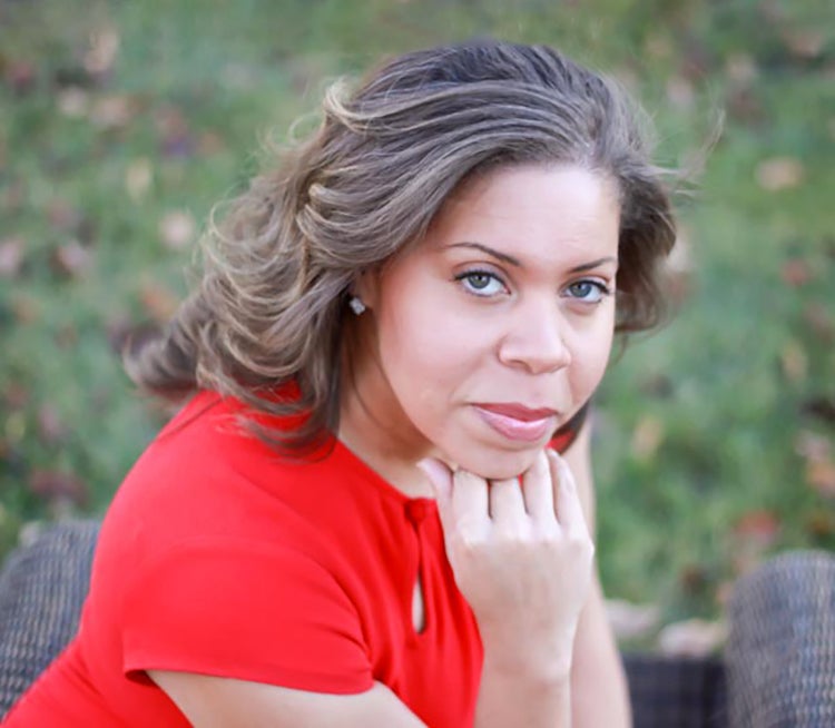 woman in red dress rests chin on right hand and looks at camera