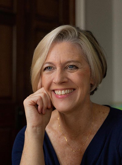 white woman in 50s/60s with silver blonde bob haircut, smiles at camera