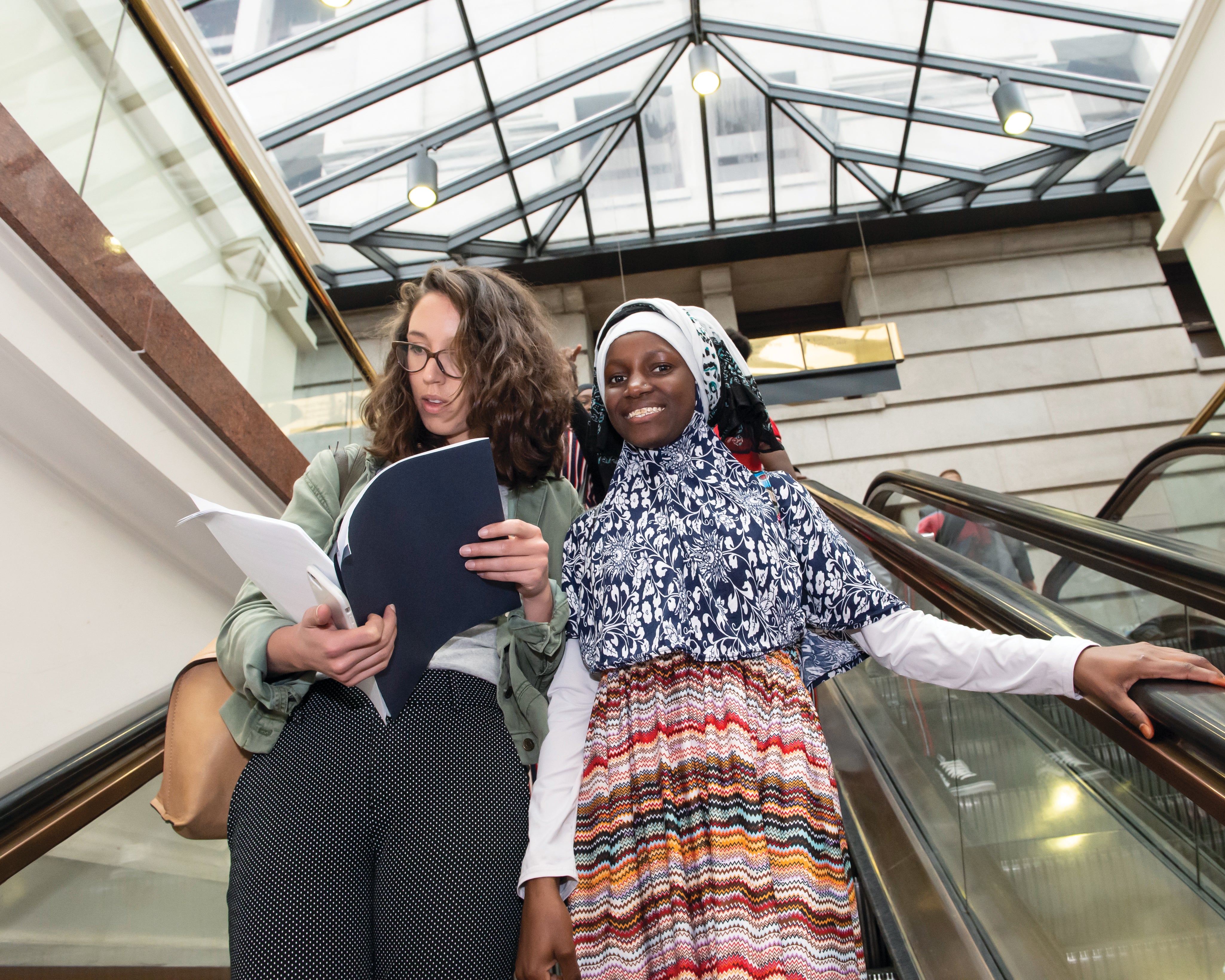 Jenna Baron and Sharifai ride down an escalator in the Pennsylvania State Capitol building.