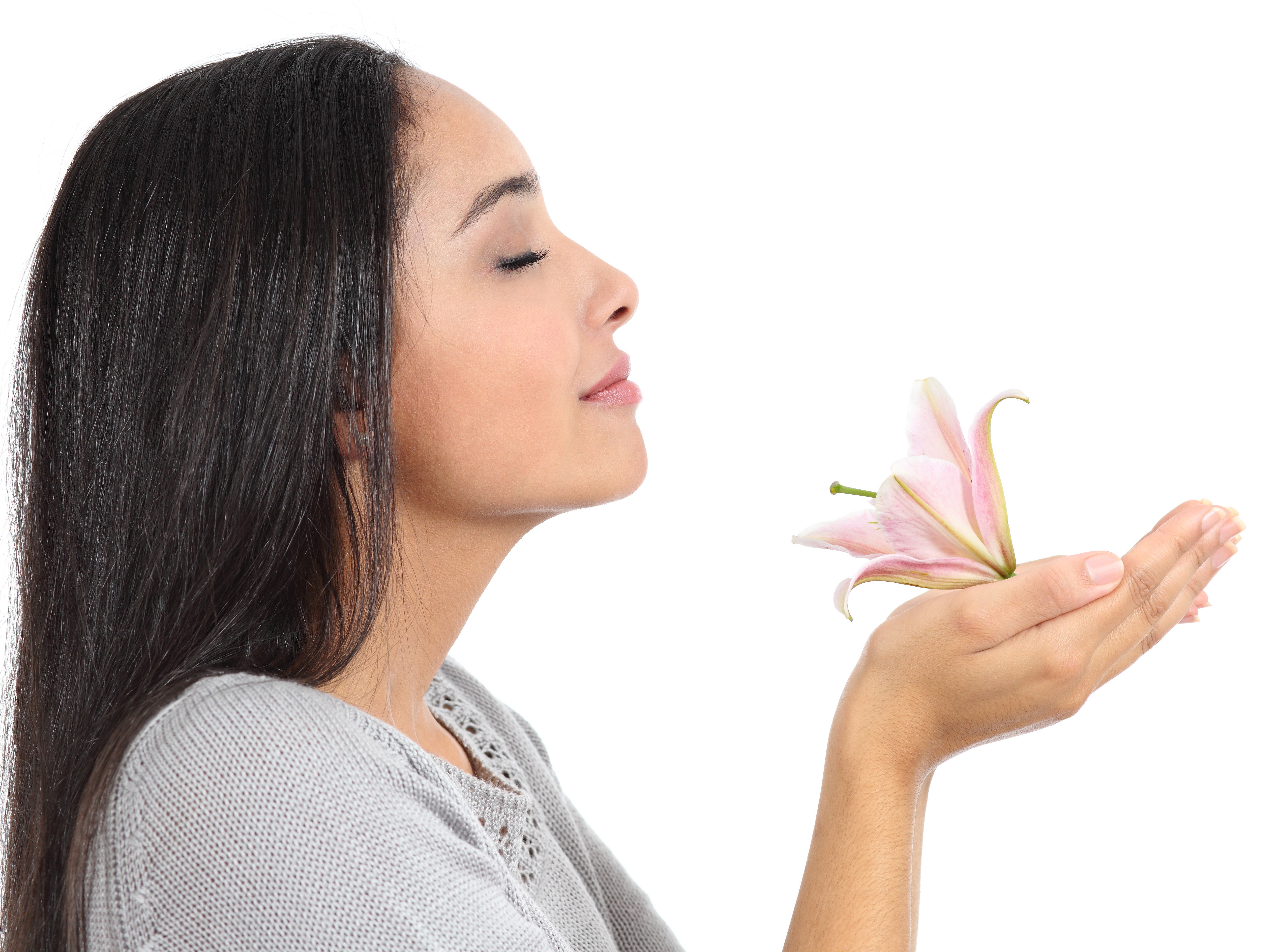 Woman sniffs pink lily she holds in her hand