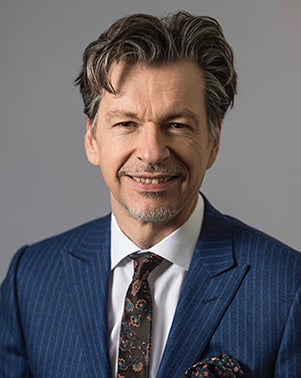 white man in blue pinstripe suit and paisley tie