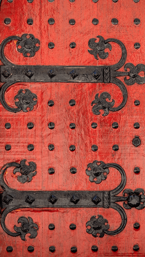 red wooden doors with ornate black iron studs and hinges