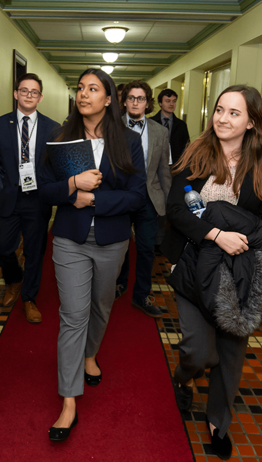 Pitt students in business wear walk down hallway together