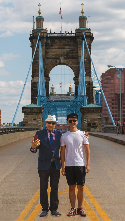 two men standing in middle of suspension bridge with bright blue detailing