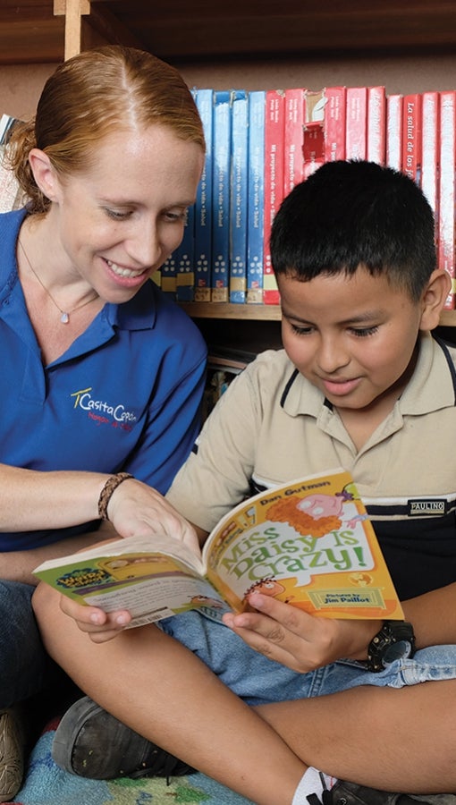 Emily Monroe helps a young boy with his English reading skills. 