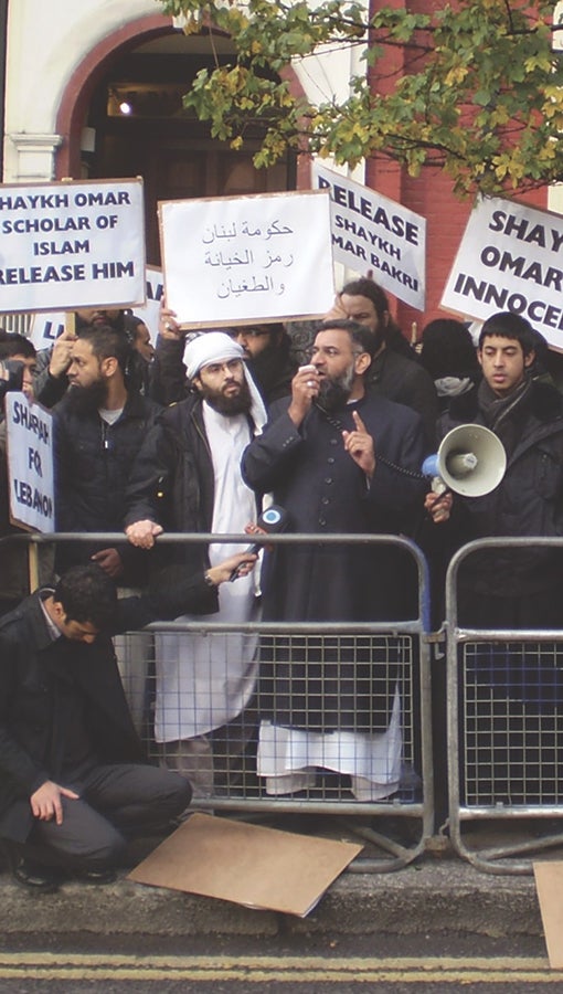 members of the Emigrants hold protest on the sidewalk, with signs in English and Arabic