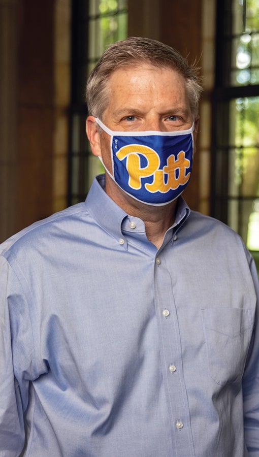 Patrick Gallagher wears a Pitt script mask in his Cathedral of Learning office