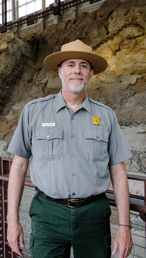 Paul Scolari in the Quarry Exhibit Hall, also called the "wall of bones," at Dinosaur National Monument