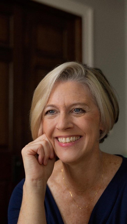 white woman in 50s/60s with silver blonde bob haircut, smiles at camera