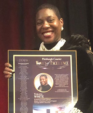 Black woman with short cropped hair holds framed plaque