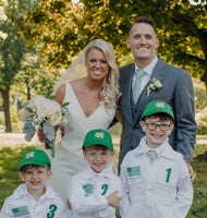 A bride and groom pose with three ringbearers in green hats