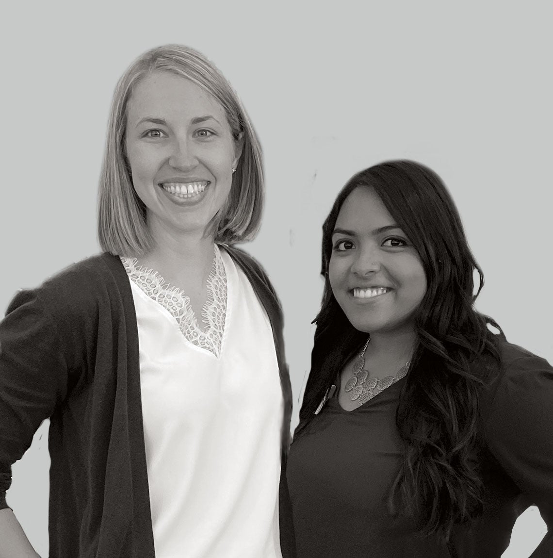 Two smiling women, one wearing white, one wearing black