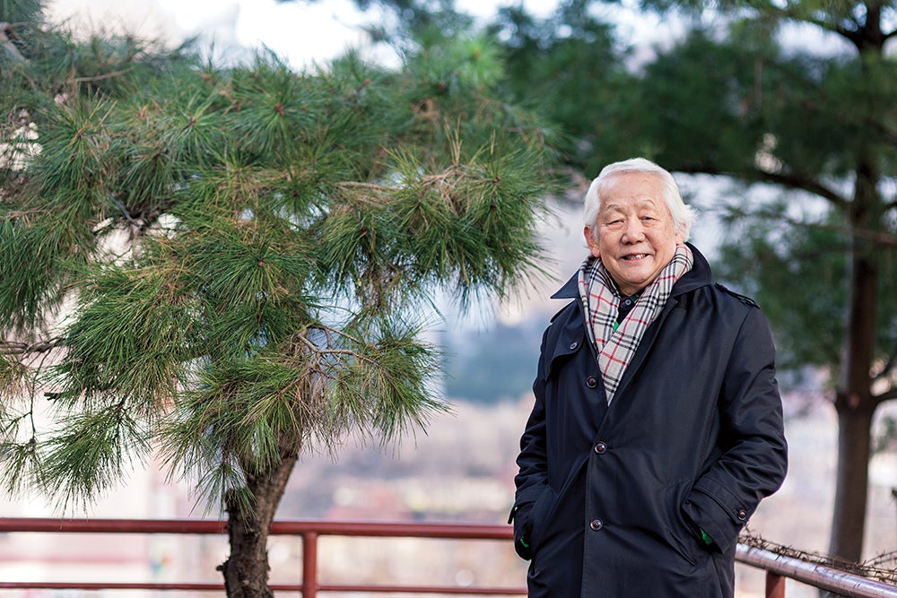 Kwon stands in front of coniferous trees.