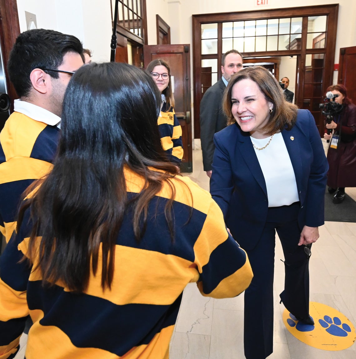 Gabel shakes hands with students in blue and yellow striped polo shirts