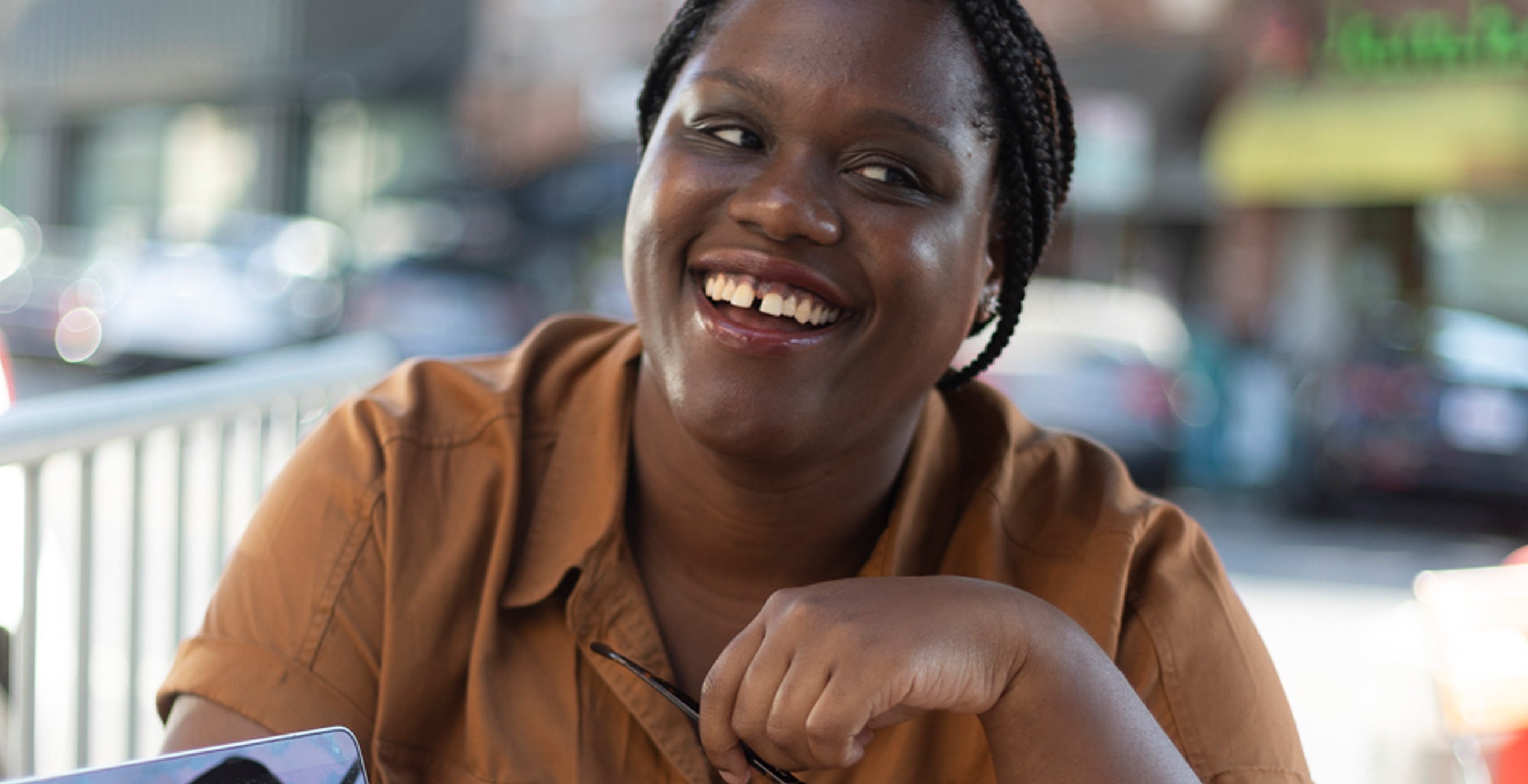 Kelechi Urama smiling with coffee and a laptop in front of her