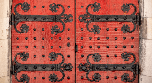 red wooden doors with ornate black iron studs and hinges