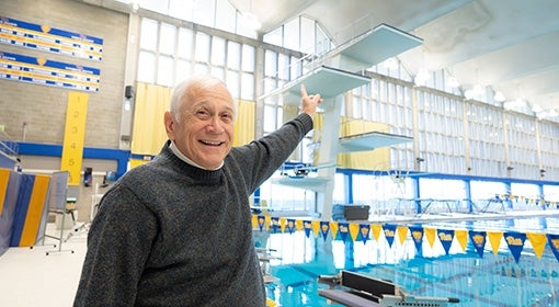 Cohen points up at a high dive over a swimming pool