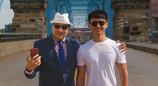 two men standing in middle of suspension bridge with bright blue detailing