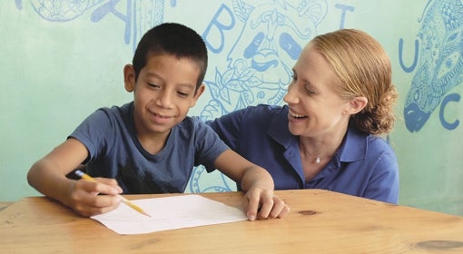 Emily Monroe helps a youngster with his writing at Casita Copán