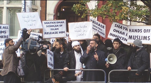 members of the Emigrants hold protest on the sidewalk, with signs in English and Arabic