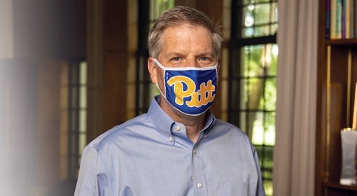 Patrick Gallagher wears a Pitt script mask in his Cathedral of Learning office