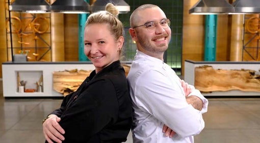 man and woman in chef coats back to back in studio kitchen