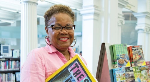 Sharon G. Flake on the first floor of Carnegie Library of Pittsburgh Main's building, holding a blow-up of the cover of The Skin I'm In.