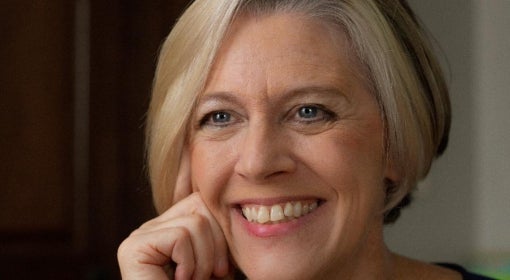 white woman in 50s/60s with silver blonde bob haircut, smiles at camera