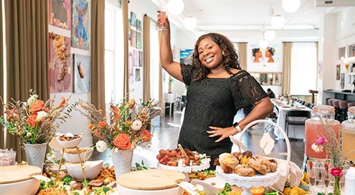Tierra Thorne lifts a glass over a table of food and flowers