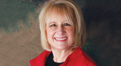 A smiling blonde woman in a red jacket