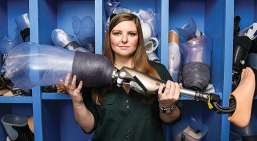 Annie Kaitlyn Caulfield stands in front of what she and her colleagues call “the graveyard,” where parts of patients’ old prostheses are kept.